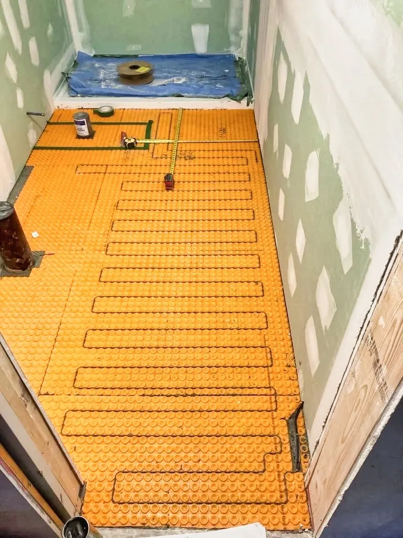 Installation d'un plancher chauffant avec membrane de désolidarisation dans une salle de bain