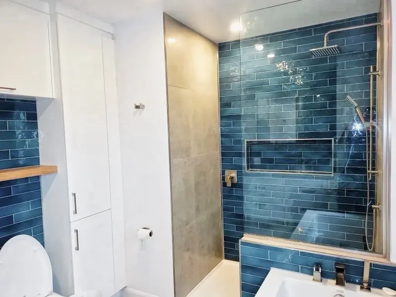 Salle de bain avec céramique bleue, douche vitrée et niche murale