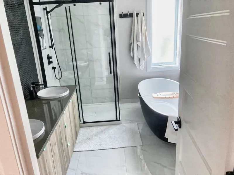 Salle de bain contemporaine rénovée par Forza Construction — baignoire autoportante et douche vitrée noire